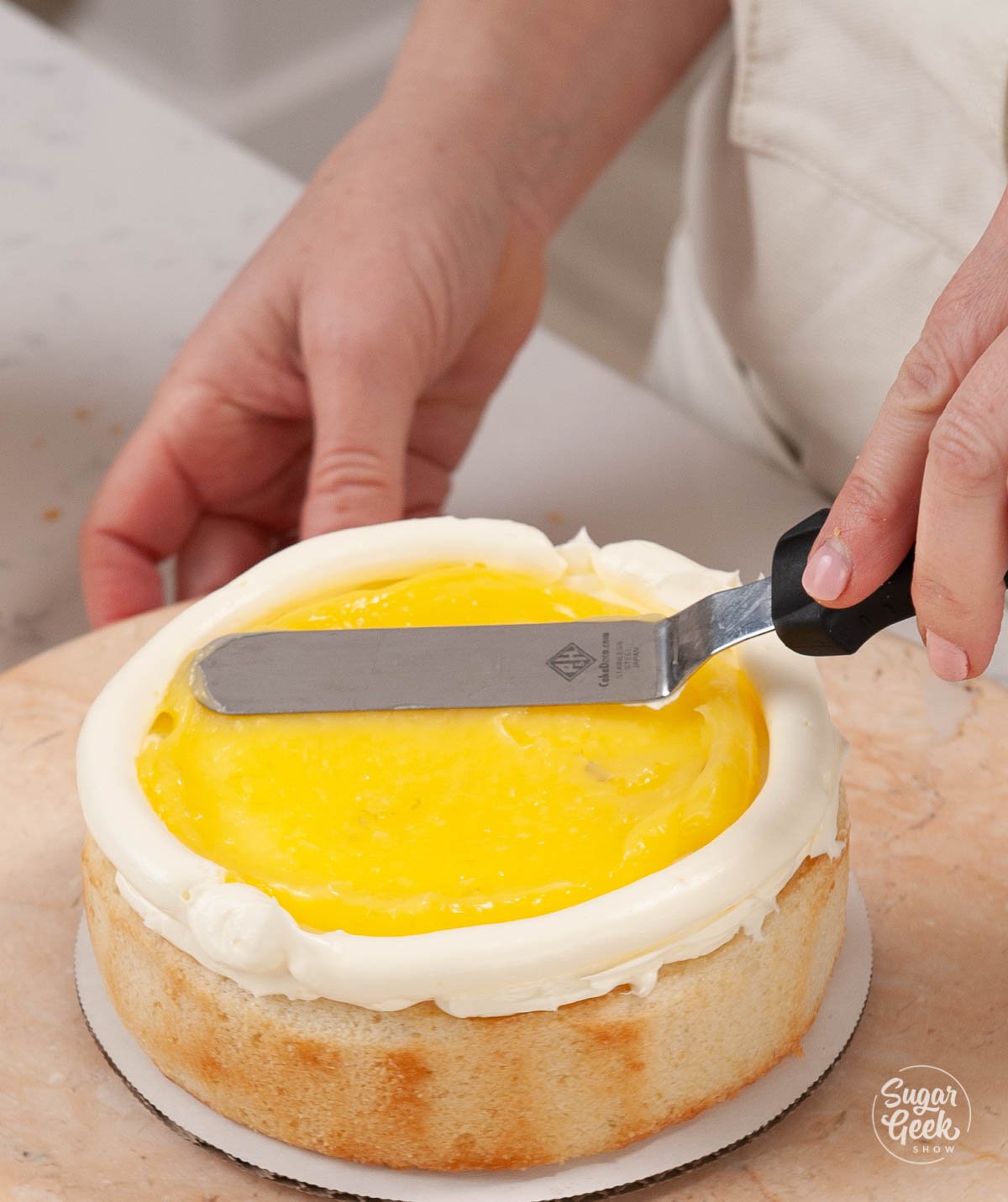 adding lime curd to cake with an offset spatula