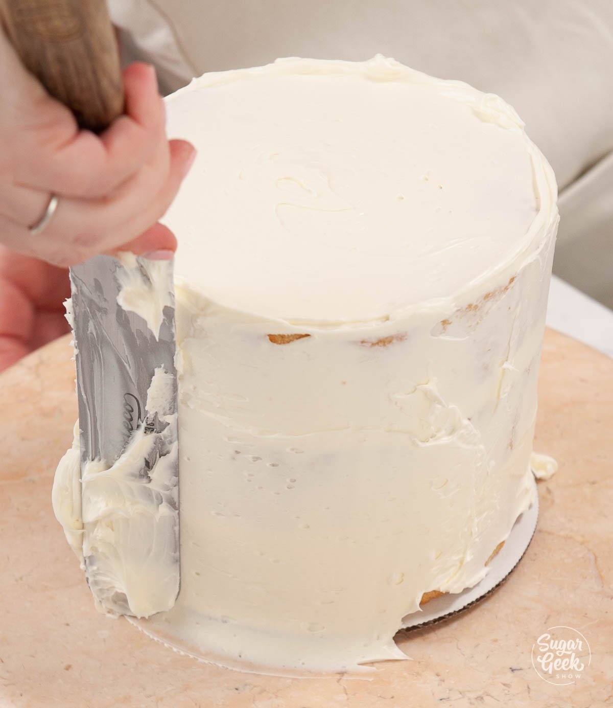 applying a crumbcoat of buttercream to the cake with an offset spatula