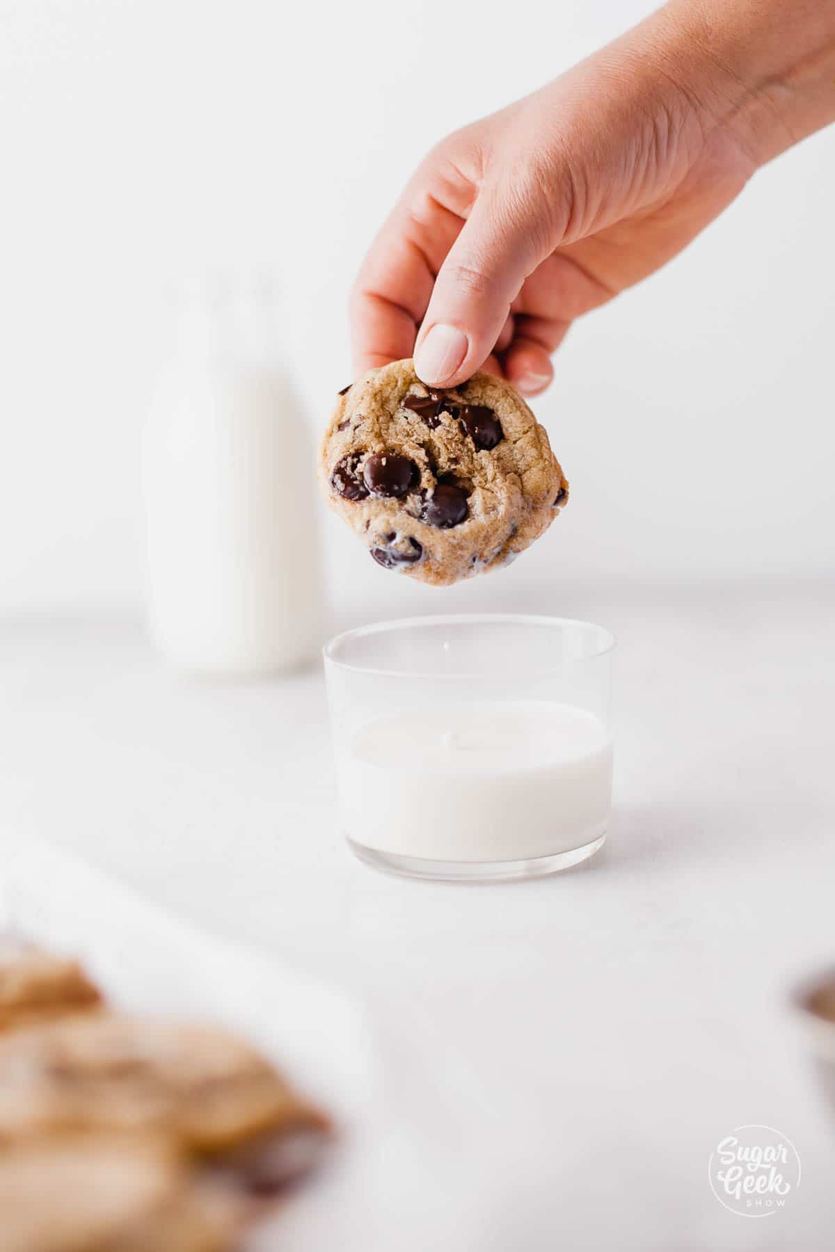 chocolate chip cookie being dunked in milk