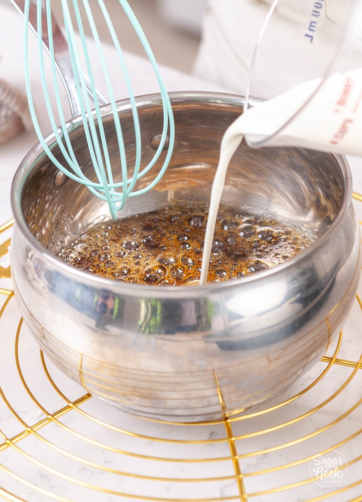 pouring and whisking cream into cooked caramel sauce pan