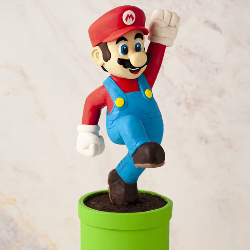 Cake scultped to look like Super Mario jumping on top of a green pipe