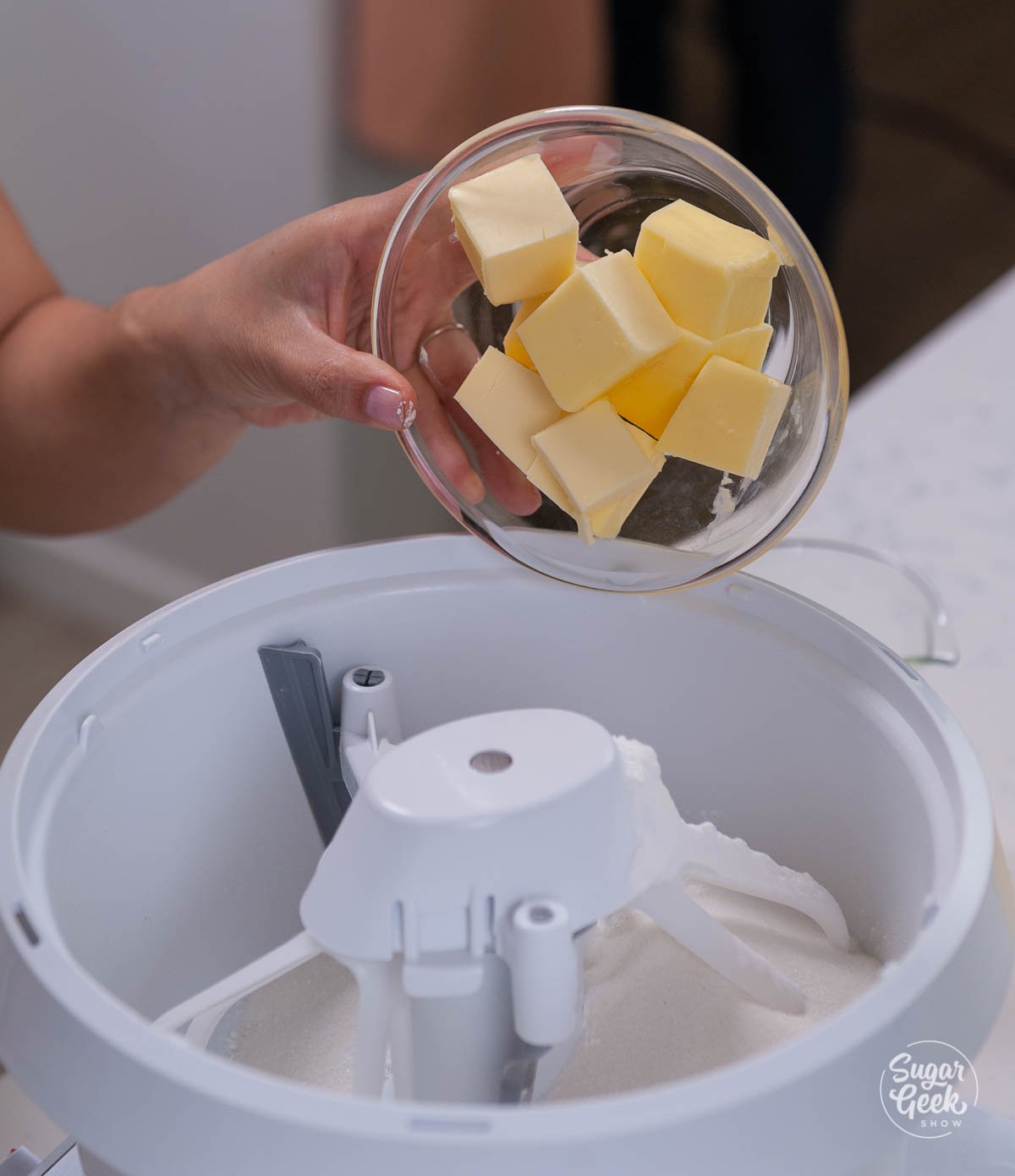 hand holding butter over dry ingredients in a mixing bowl