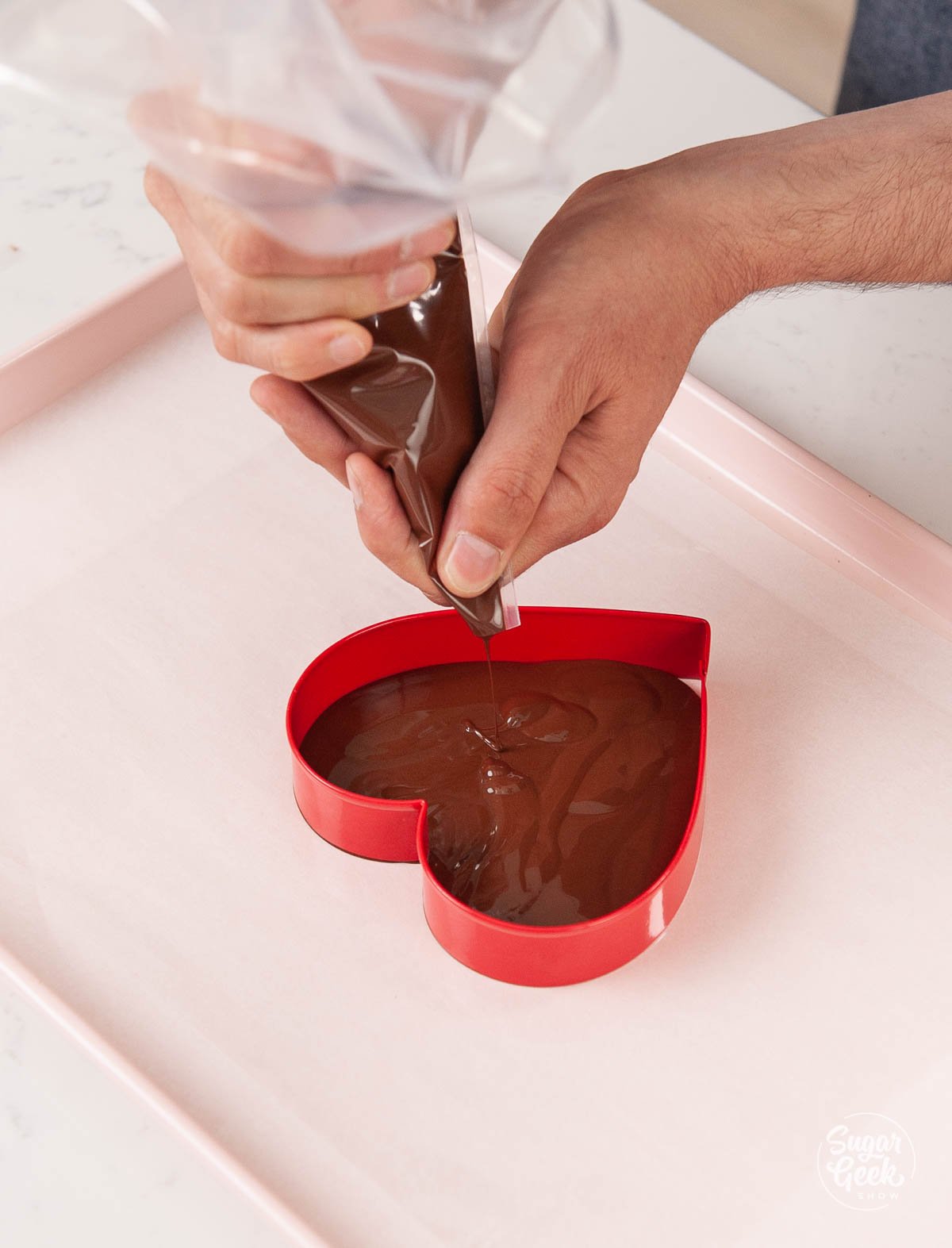 Pouring tempered chocolate into a heart cookie cutter