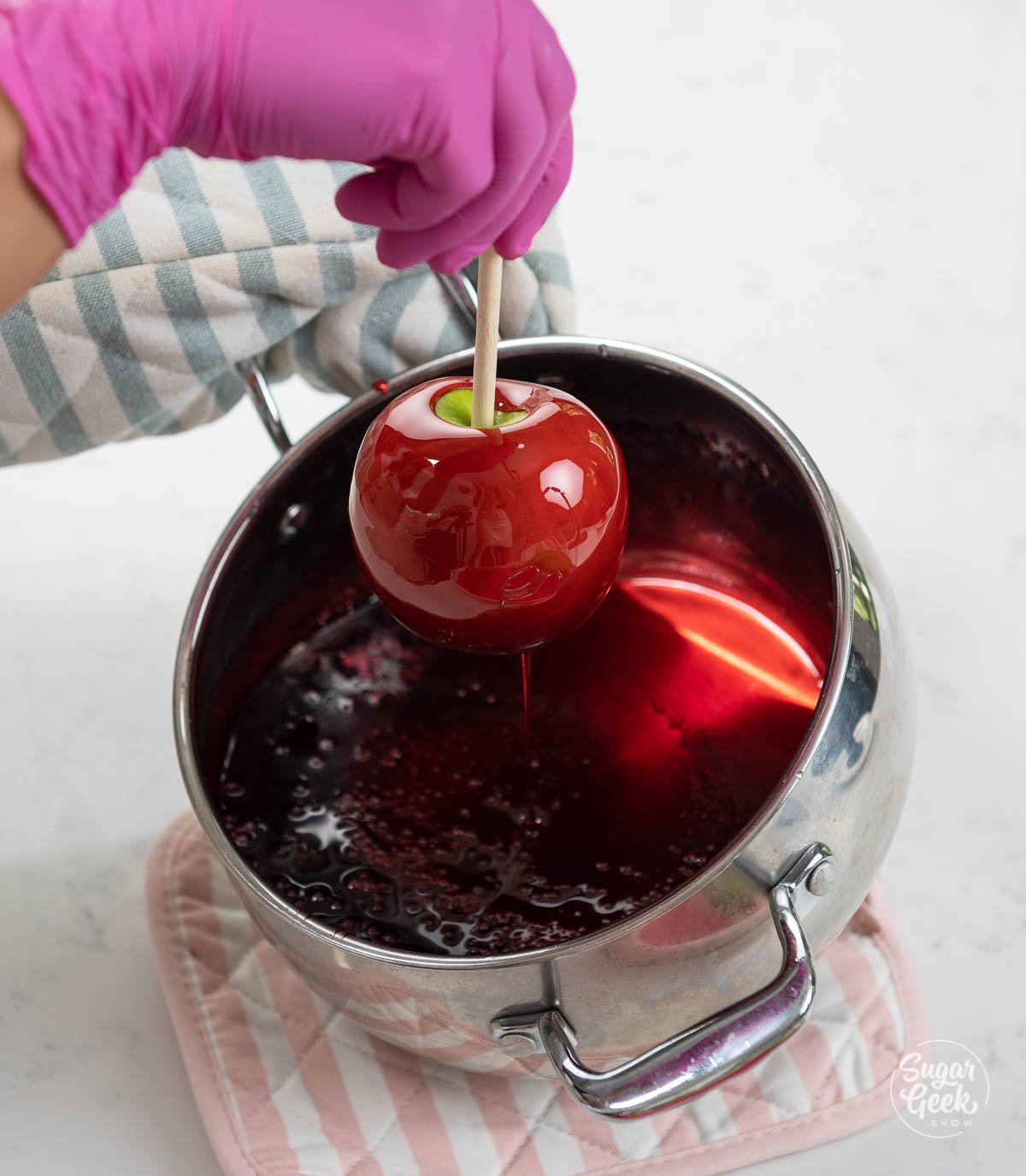 lifting a candy apple out of the candy mixture