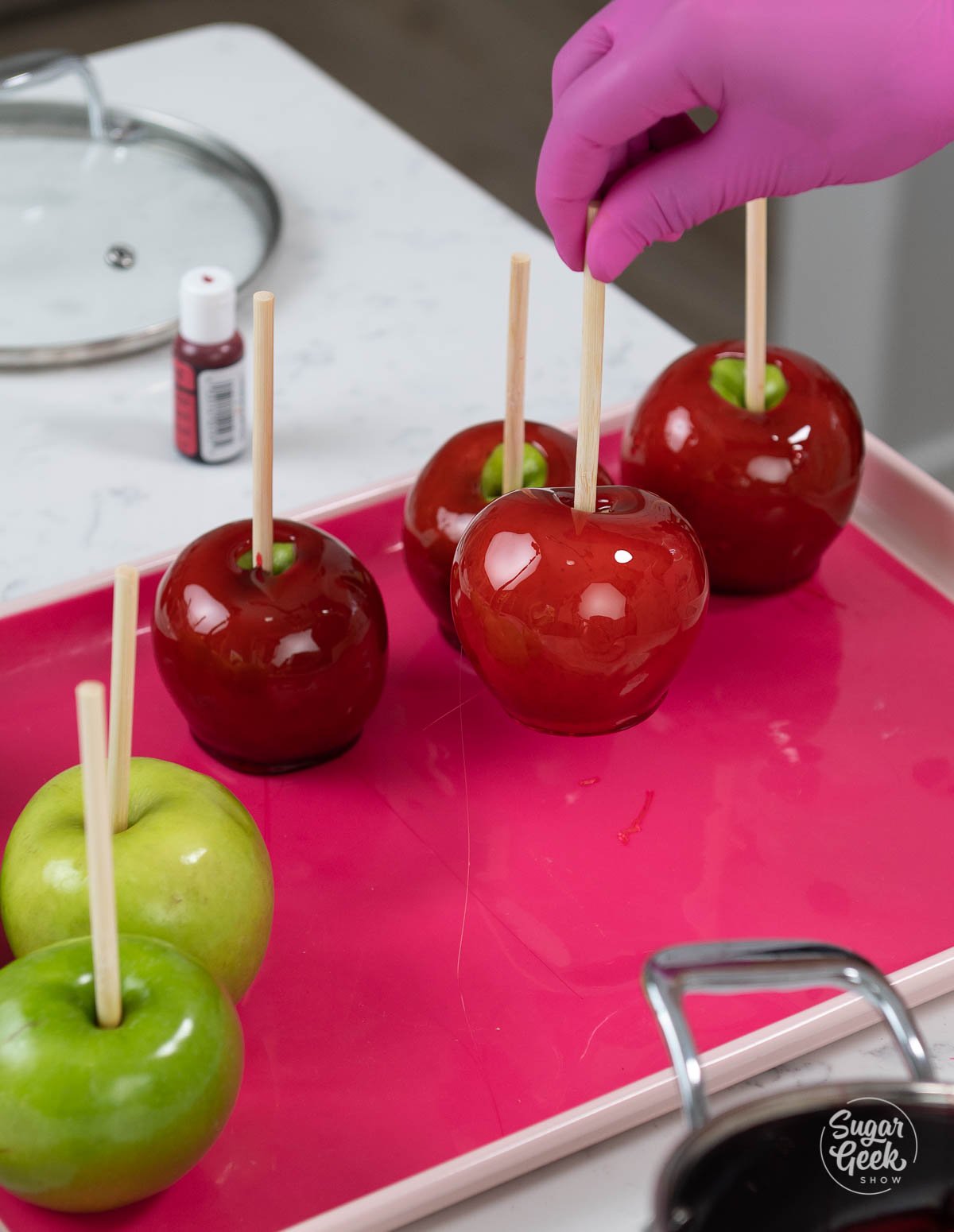 close up of candy apples being placed onto a pink silicone mat