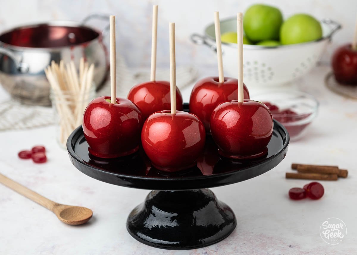 close up of candy apples on a black cake pedestal