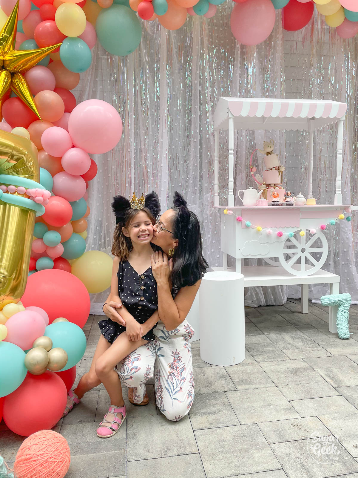 mom kissing daughter next to balloons