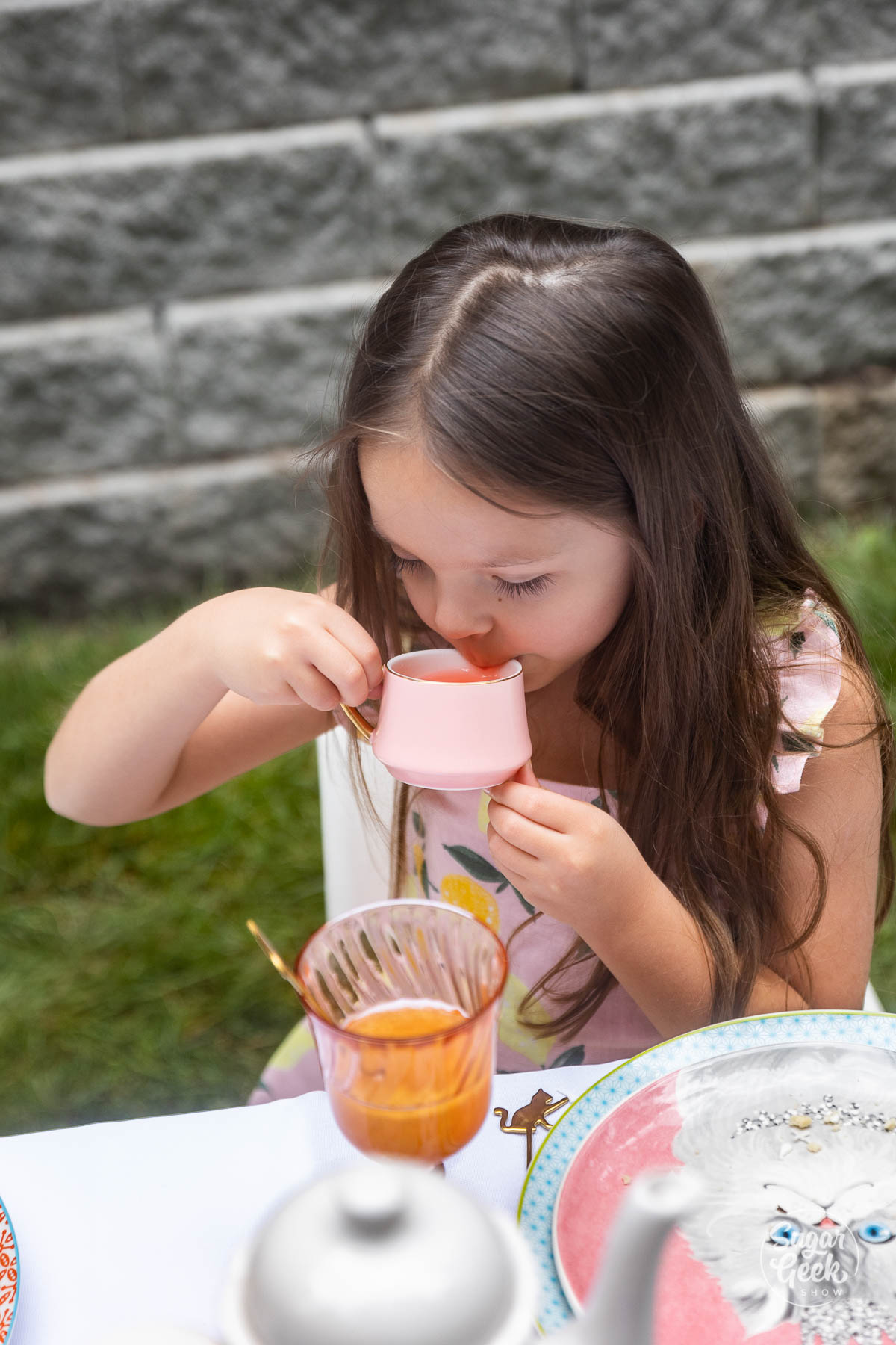 little girl drinking from a small teacup