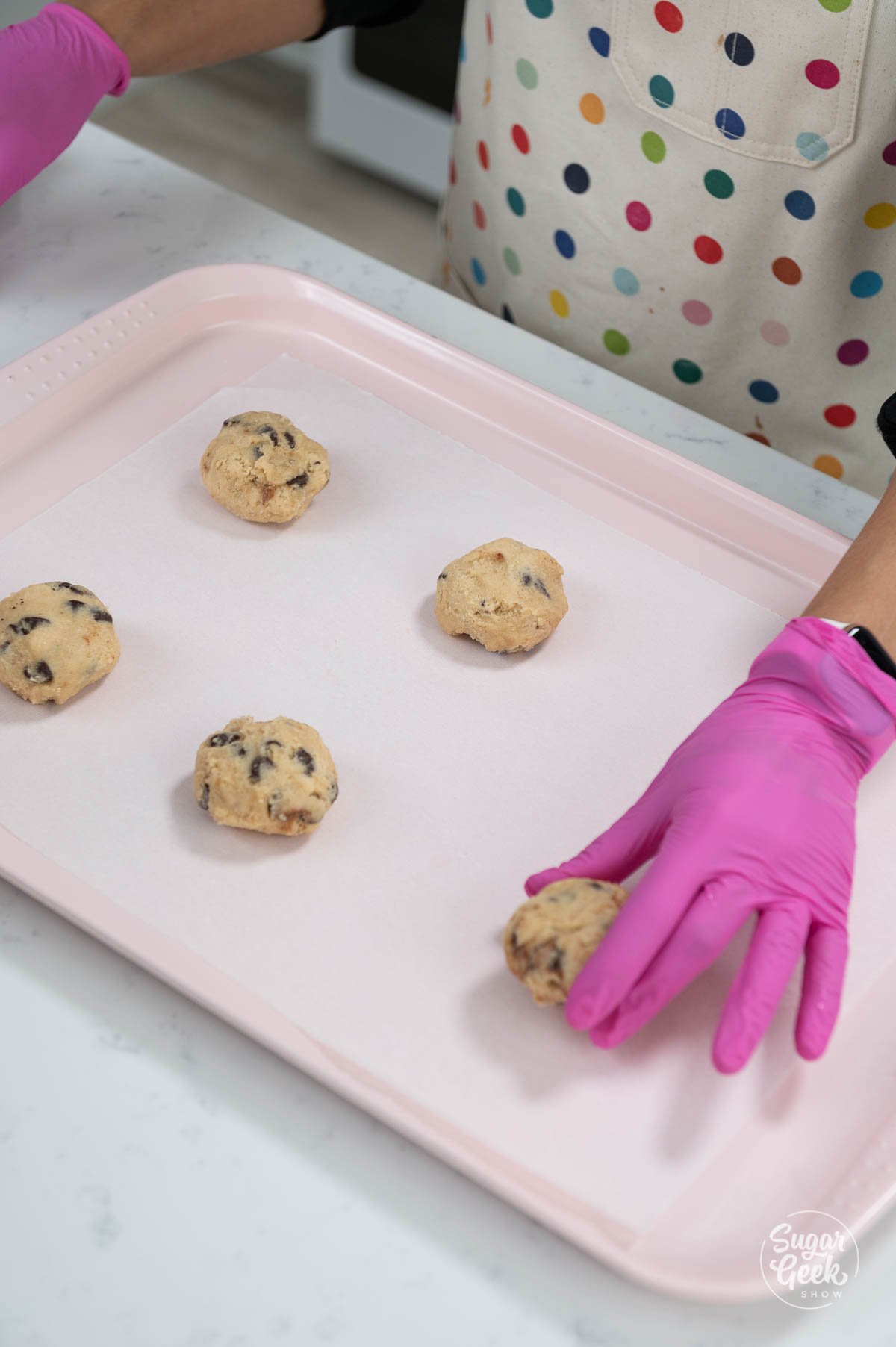 placing cookie dough balls on a sheet pan with parchment paper