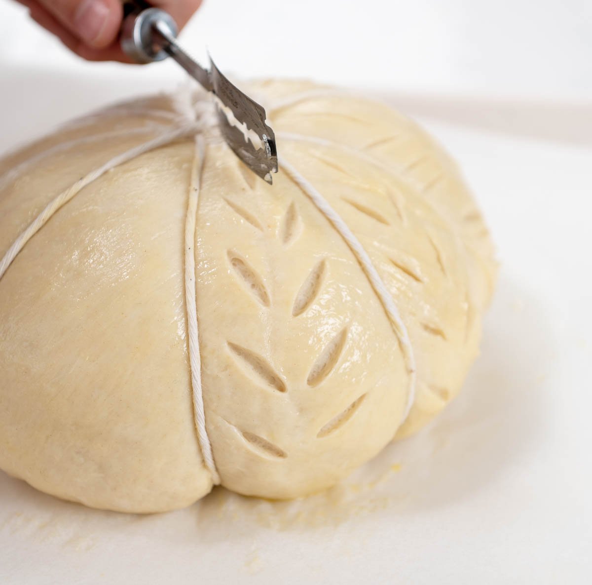 Cutting slits into the bread dough with a razorblade
