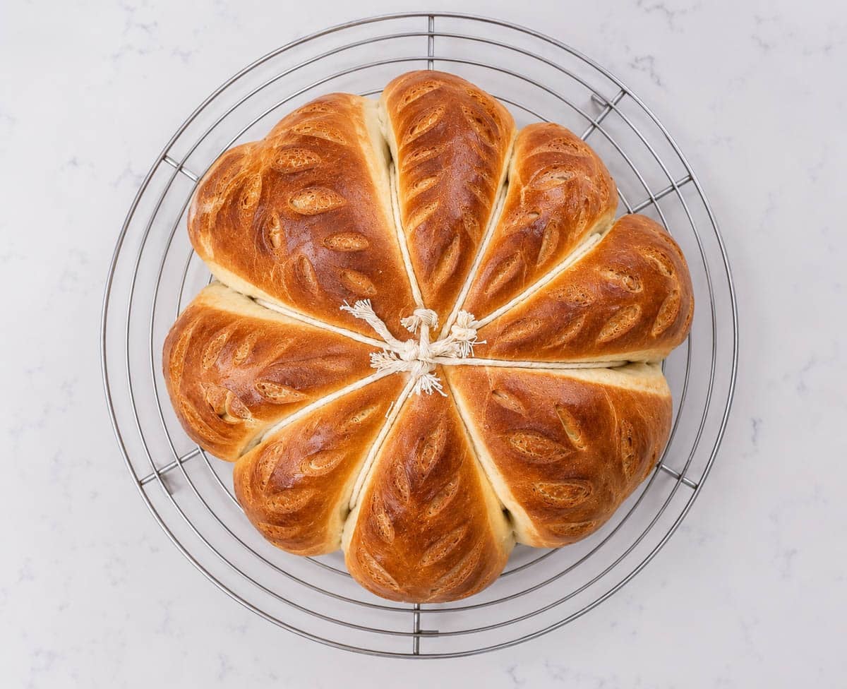 Baked pumpkin shaped bread on a cooling rack.