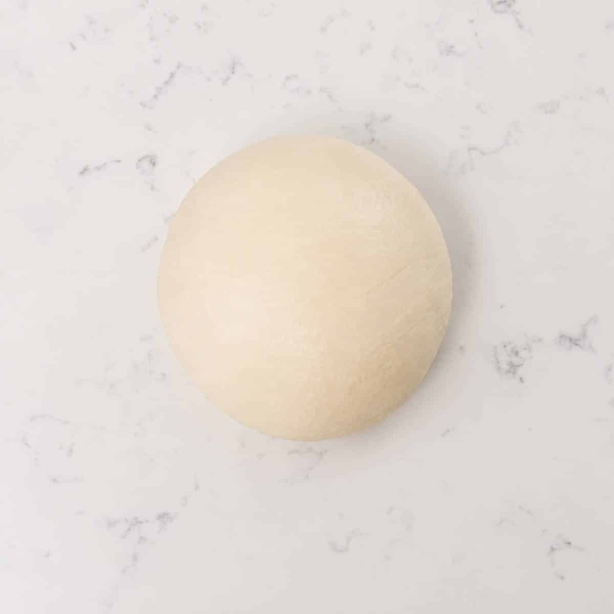 Bread dough shaped into a smooth ball.
