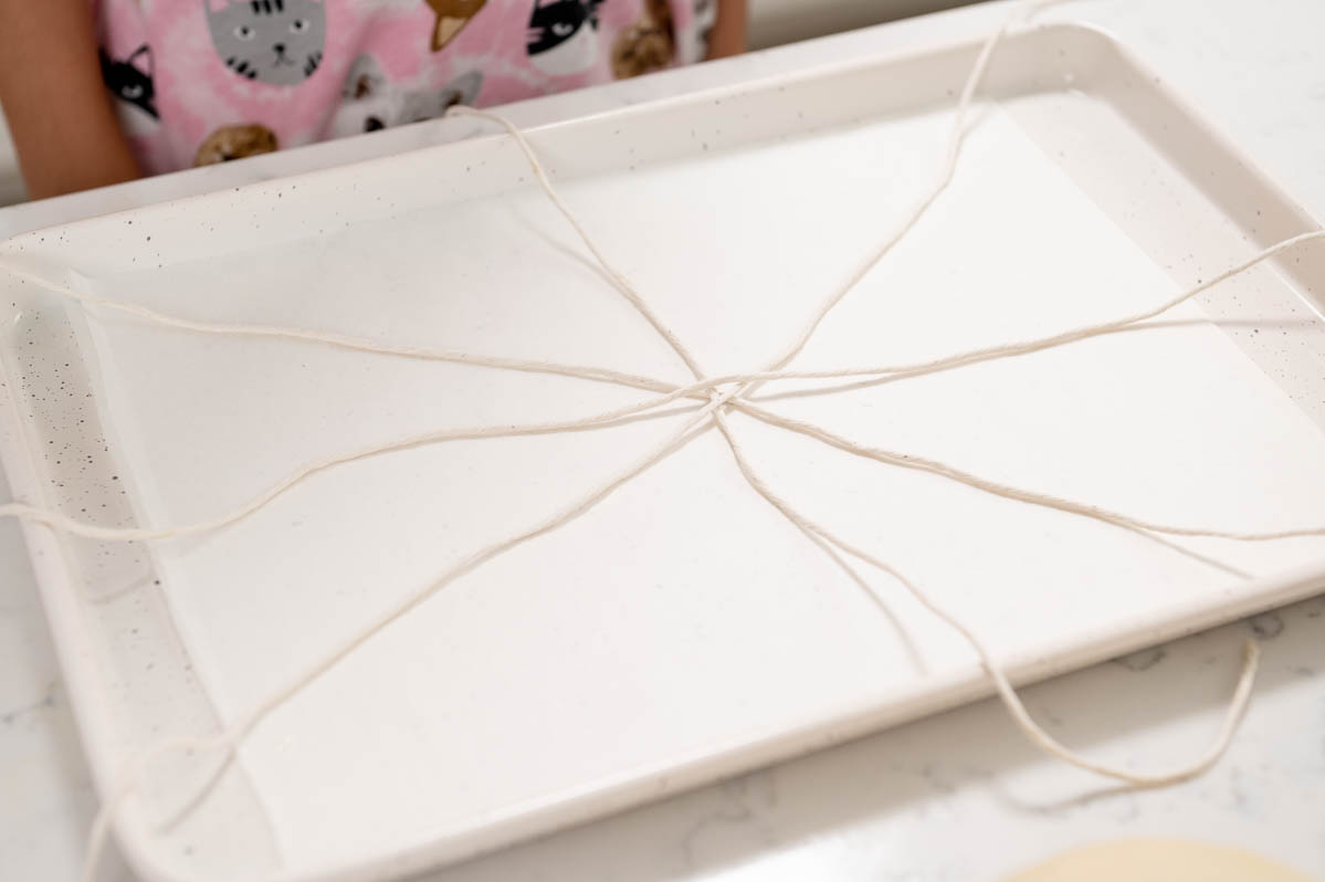 bakers twine laid in a criss cross pattern on a parchment paper lined sheet pan