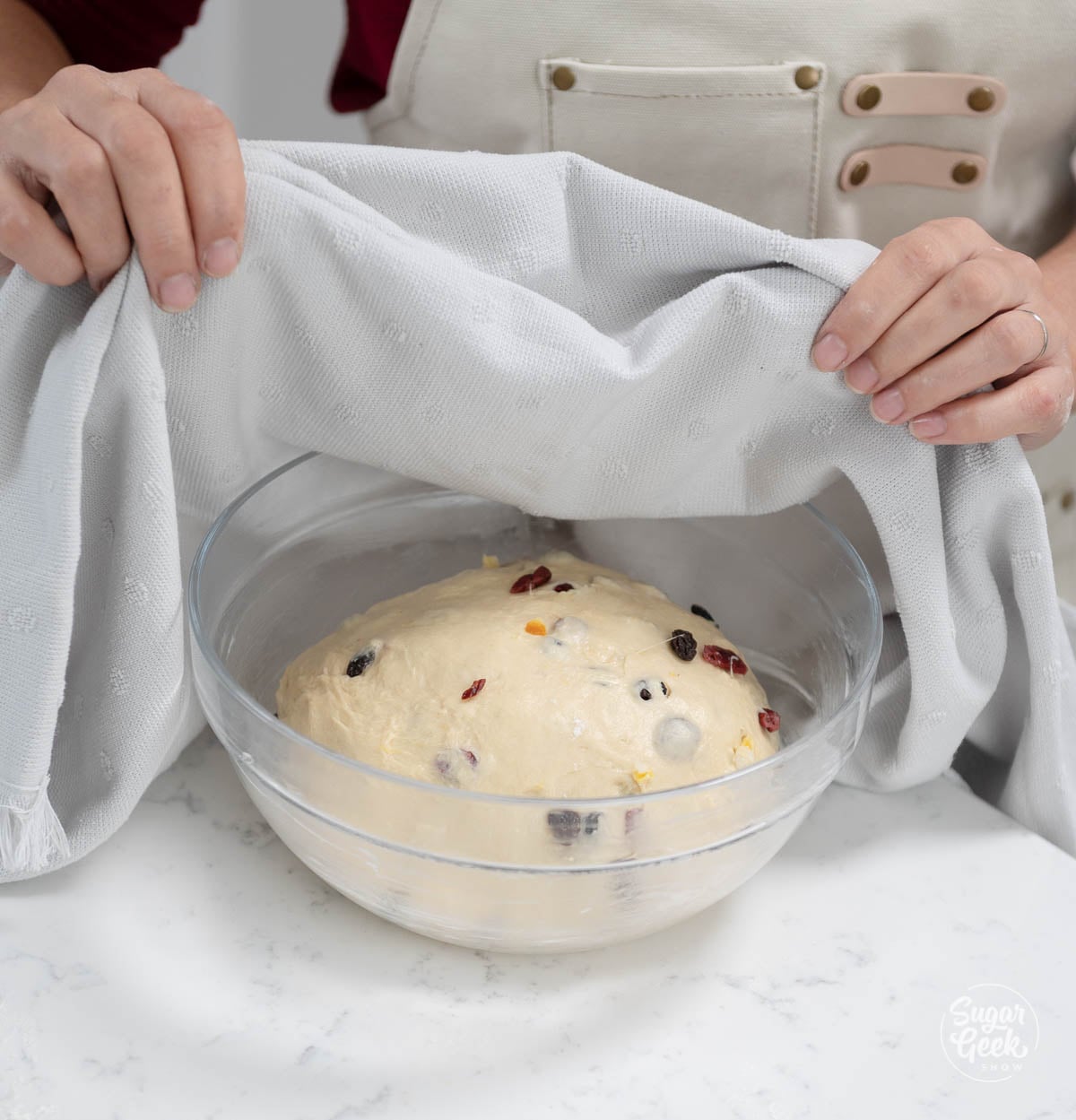 The bowl with the panettone dough is being covered with a cloth to rise.