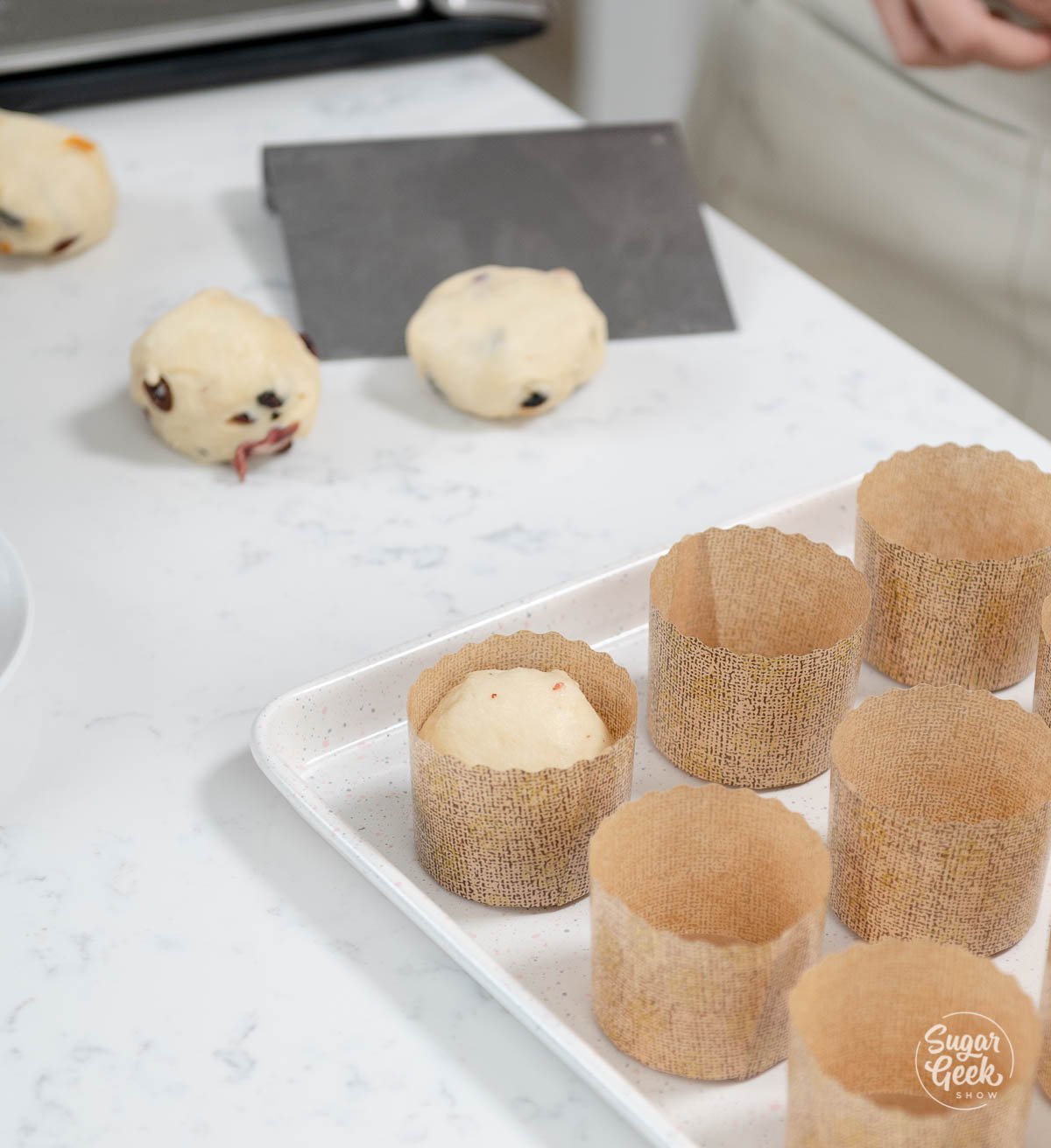 placing panettone dough balls in panettone wrappers