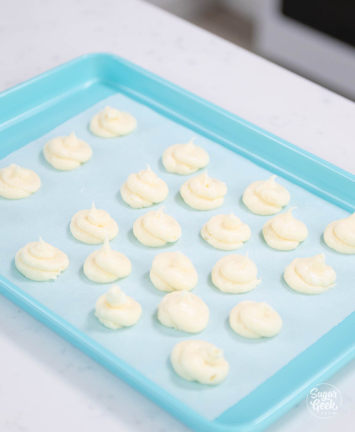 cream cheese filling dollops on a blue sheet pan with parchment paper