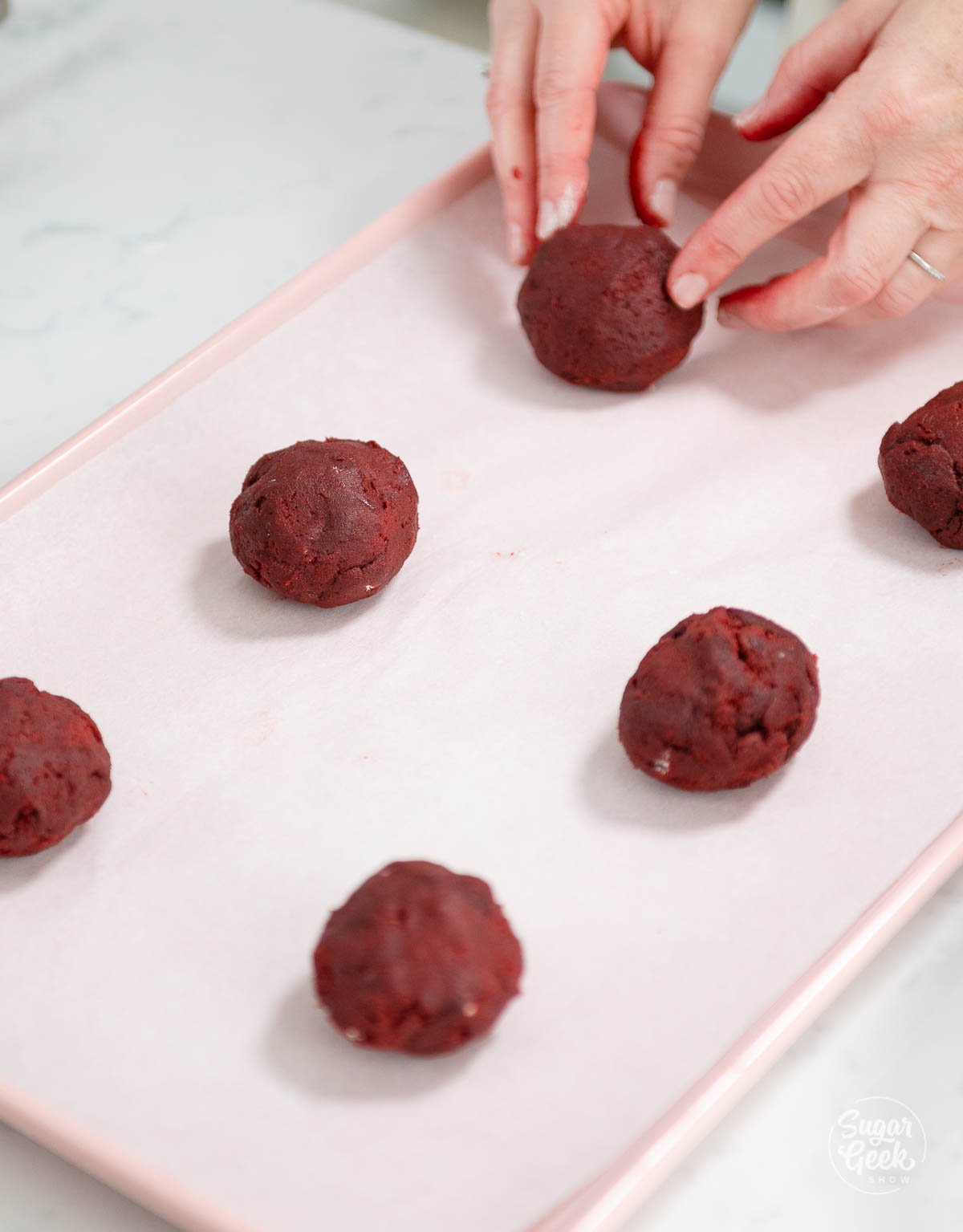 balls of red velvet cookie dough on a cookie sheet