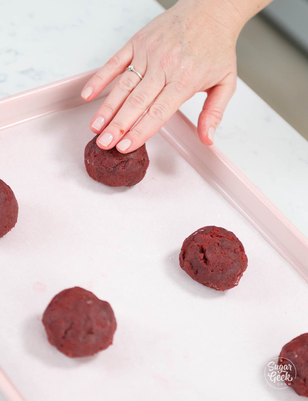placing red velvet cookie dough onto a sheet pan