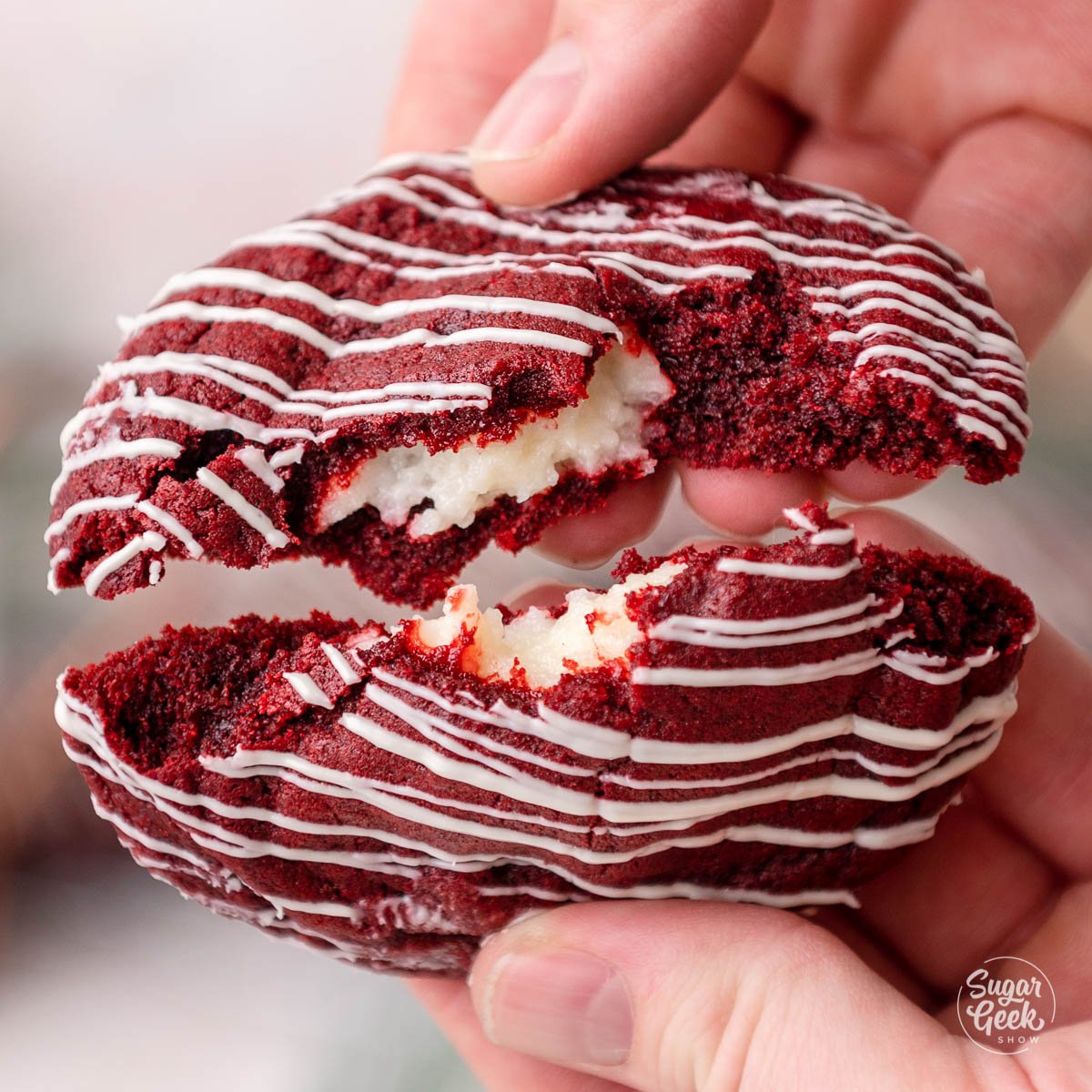 hands breaking a red velvet cookie in half