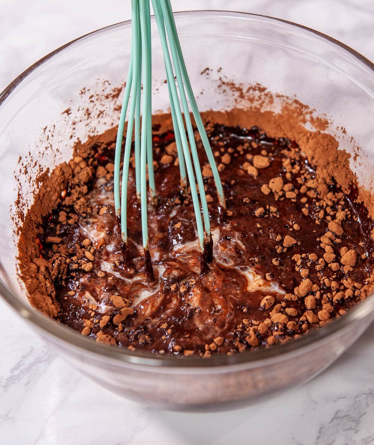 close up of melted butter and cocoa powder being whisked in a glass bowl