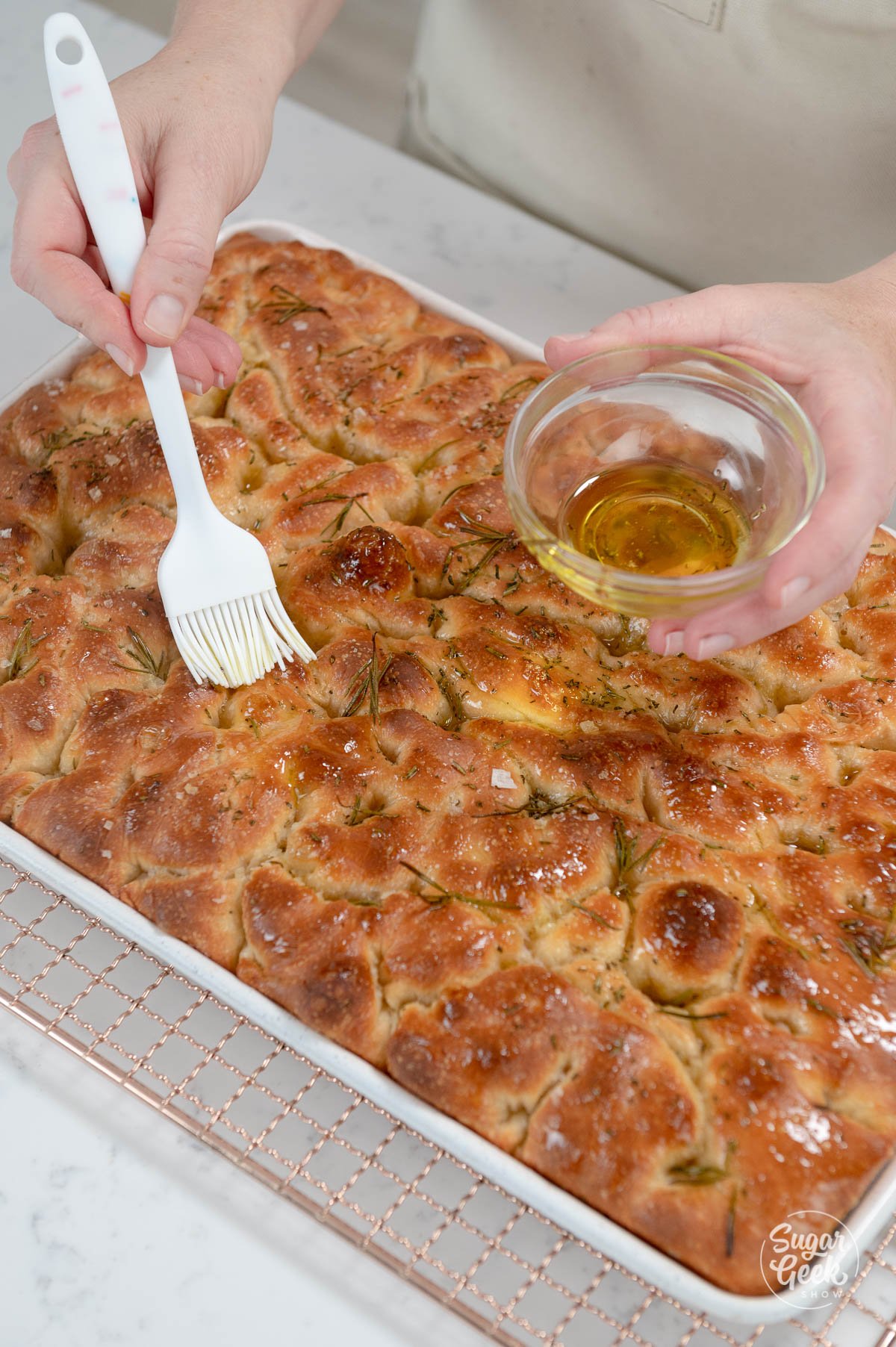brushing focaccia with more olive oil