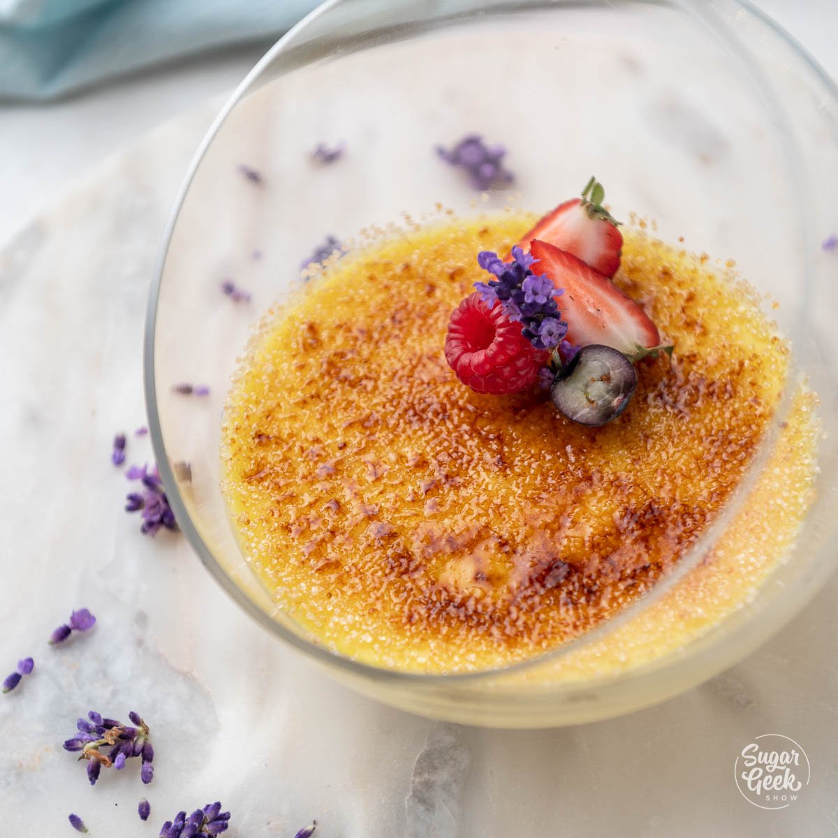 crème brûlée in a glass dish decorated with fruits and a flower