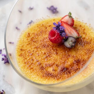 crème brûlée in a glass dish decorated with fruit and flowers