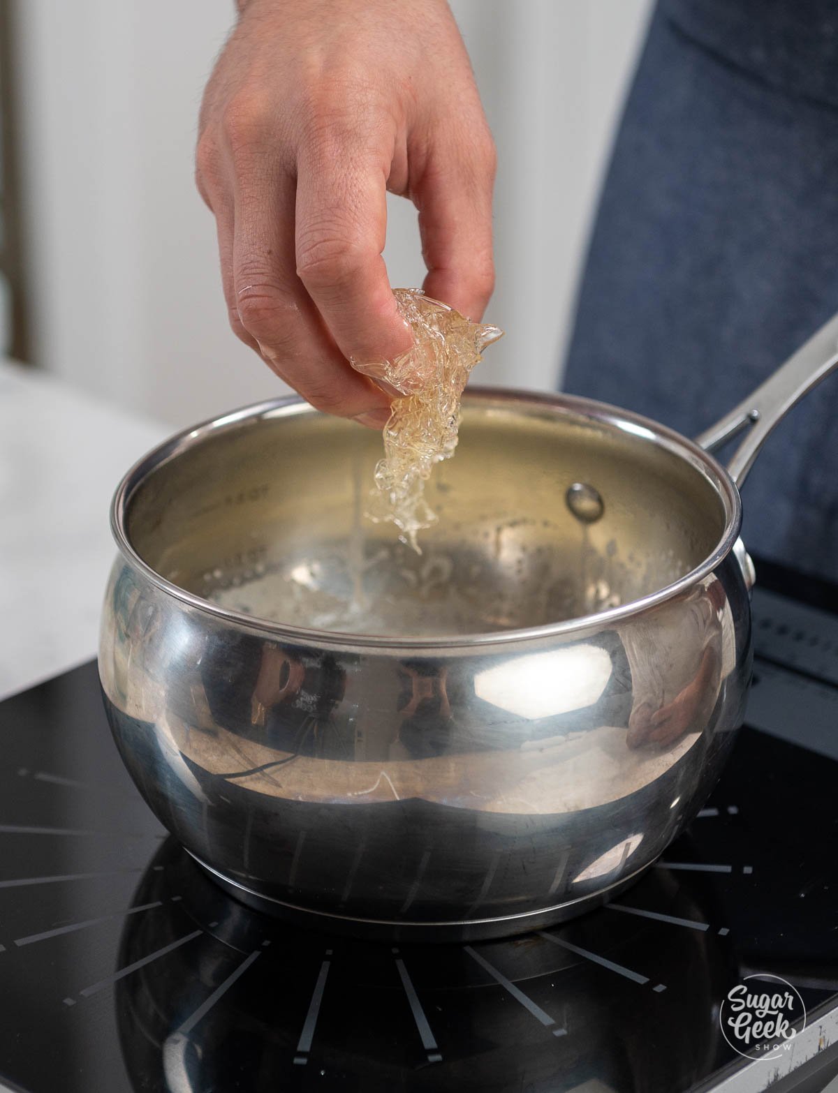 hand dropping gelatin inside of a saucepan