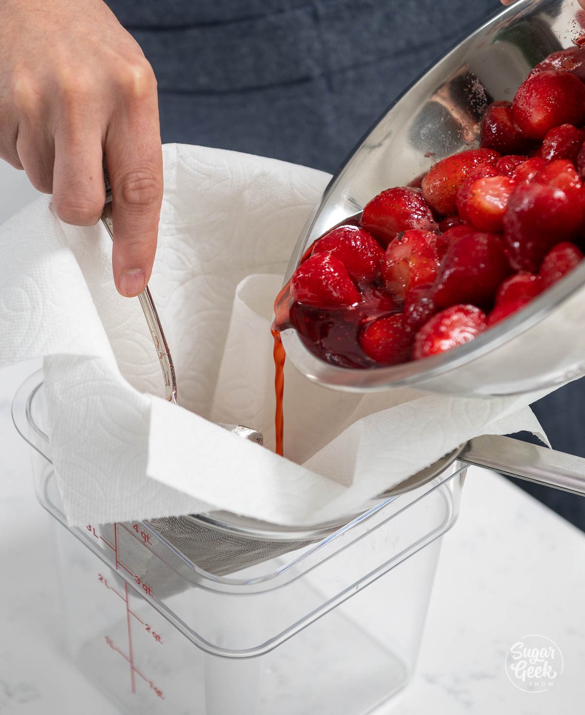 hand guiding a bowl of strawberries through a strainer