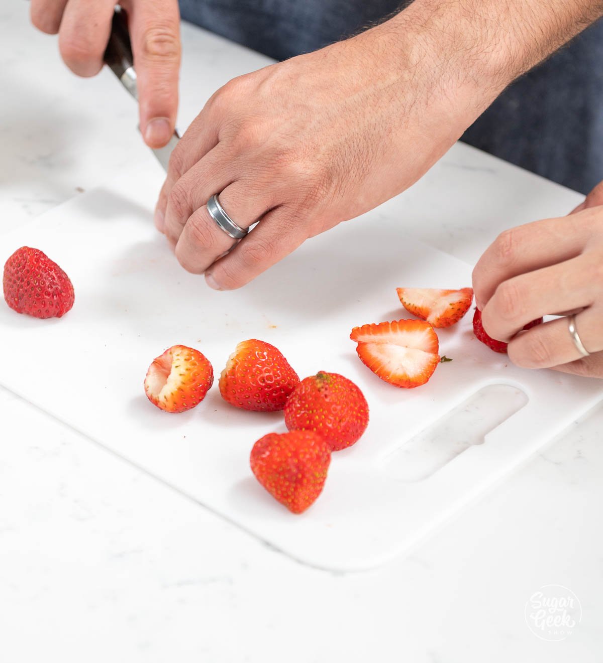 hands shown chopping up strawberries