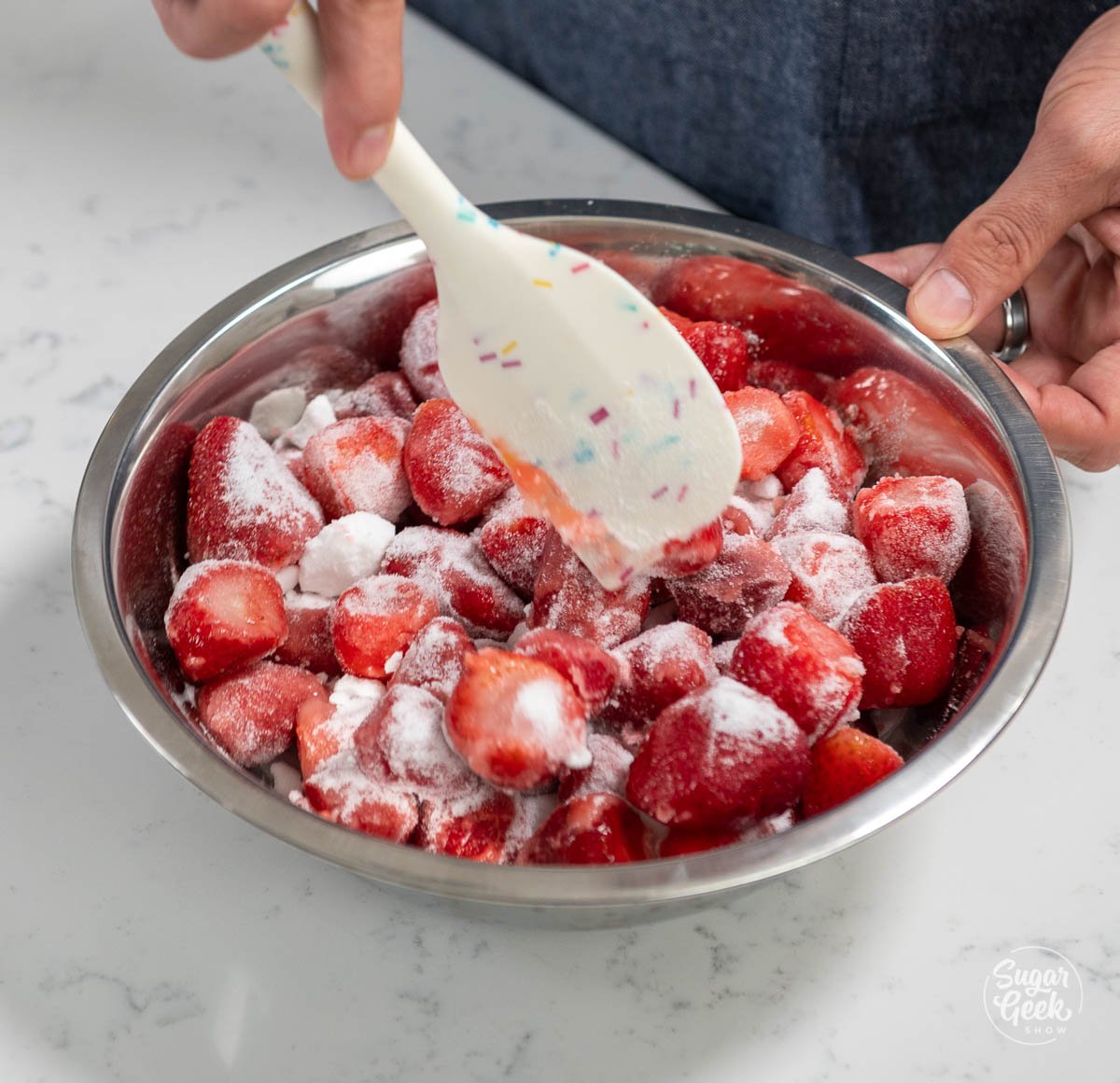 mixing strawberries and sugar together with a spatula