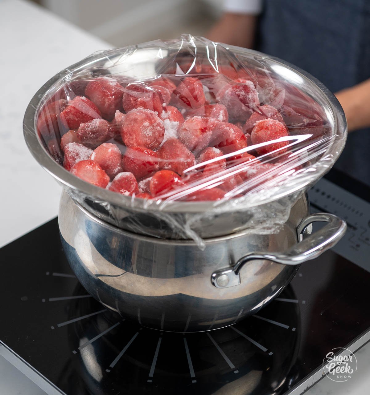 bowl of strawberries on oven covered with plastic wrap