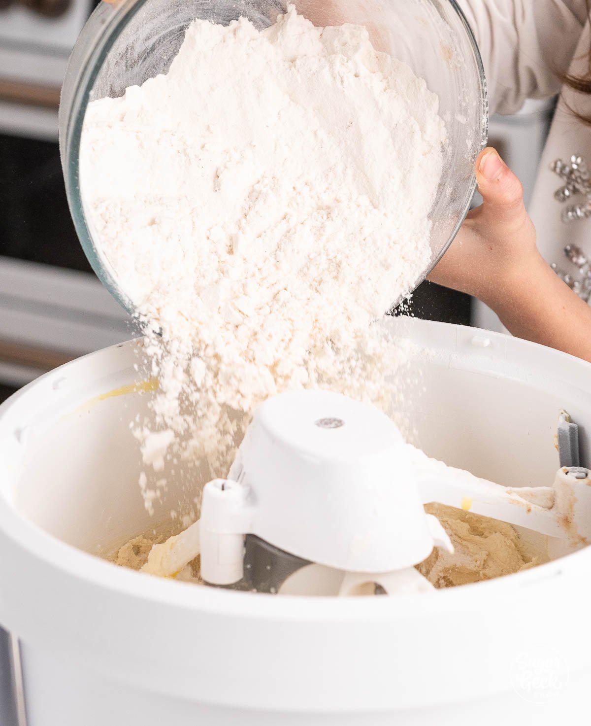 adding flour into the bowl of a stand mixer