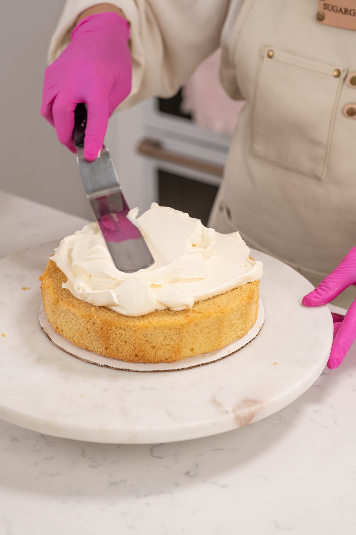 adding buttercream to the first layer of cake