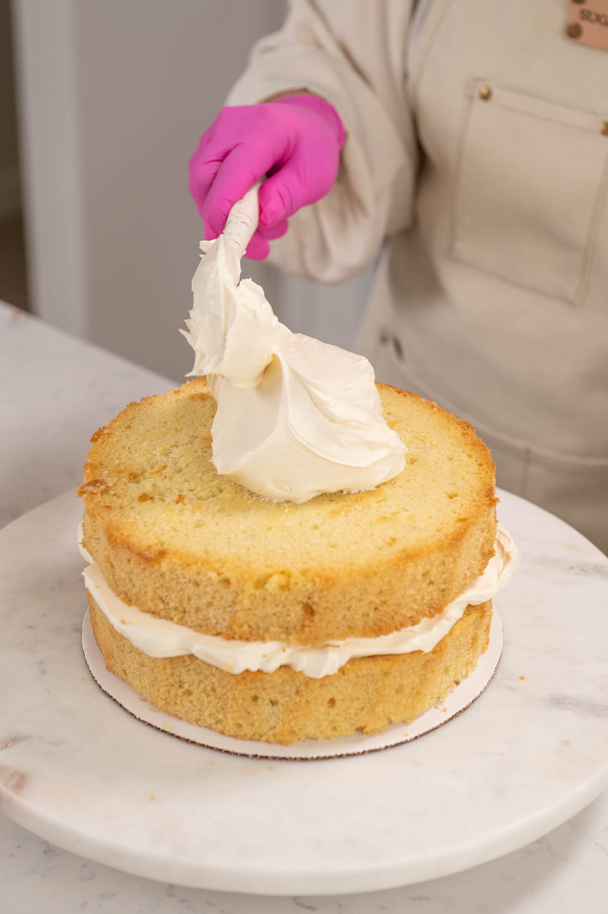 adding buttercream to cake layers