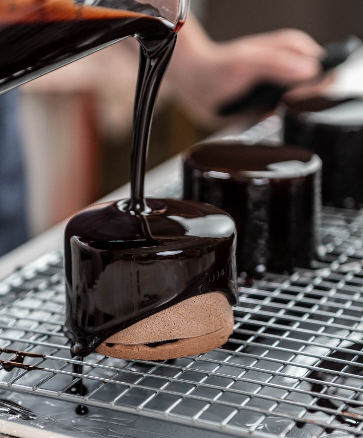 pouring chocolate glaze over chocolate entremet