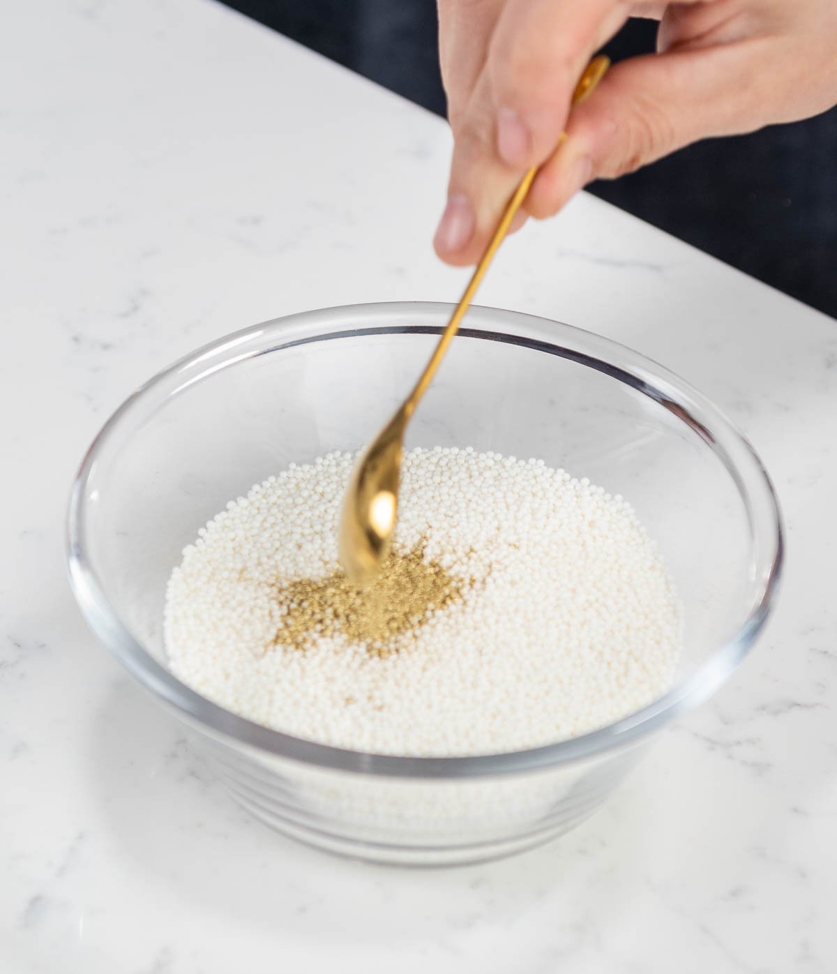 hand mixing edible gold dust in sprinkles