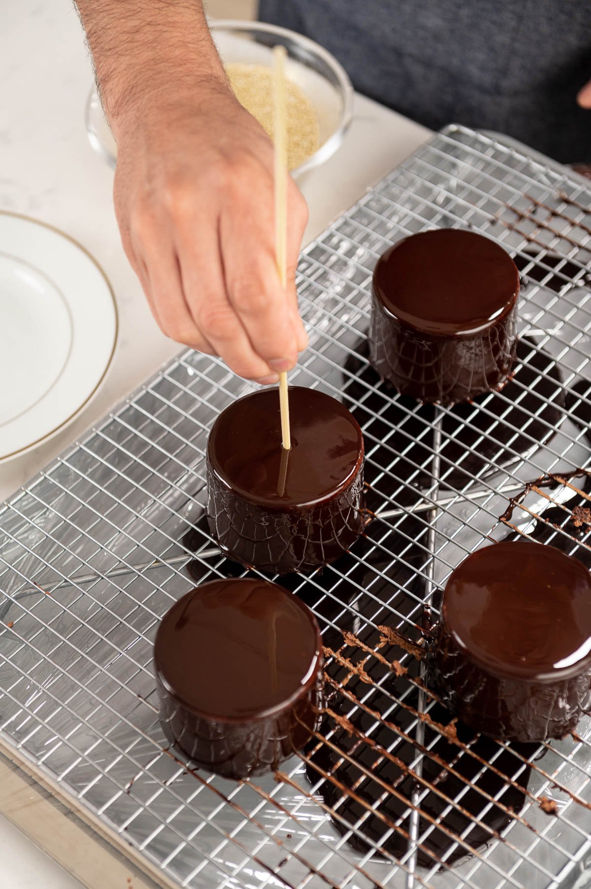 hand placing toothpick inside of chocolate entremet