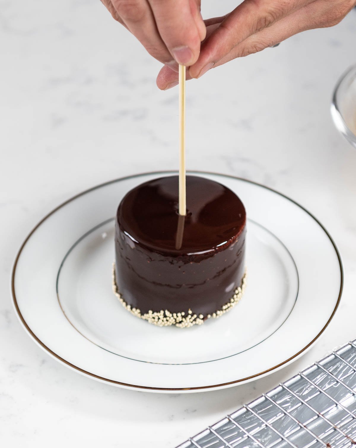 hand placing toothpick inside of chocolate entremet