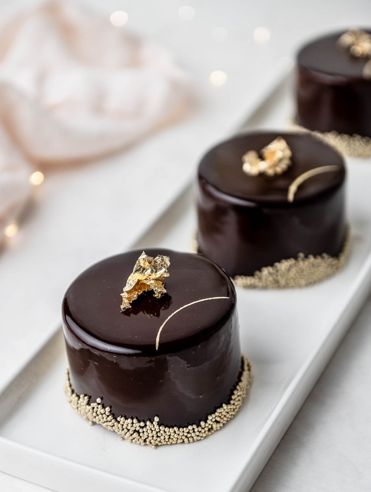 chocolate entremets on a plate with edible gold decorations