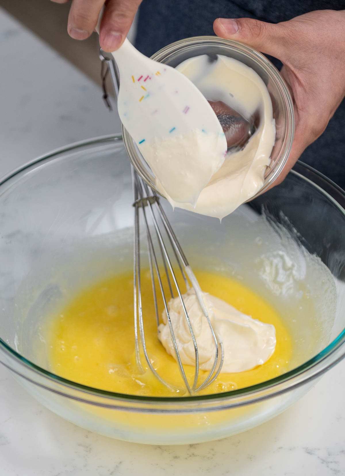 using spatula to transfer ingredient to mixing bowl