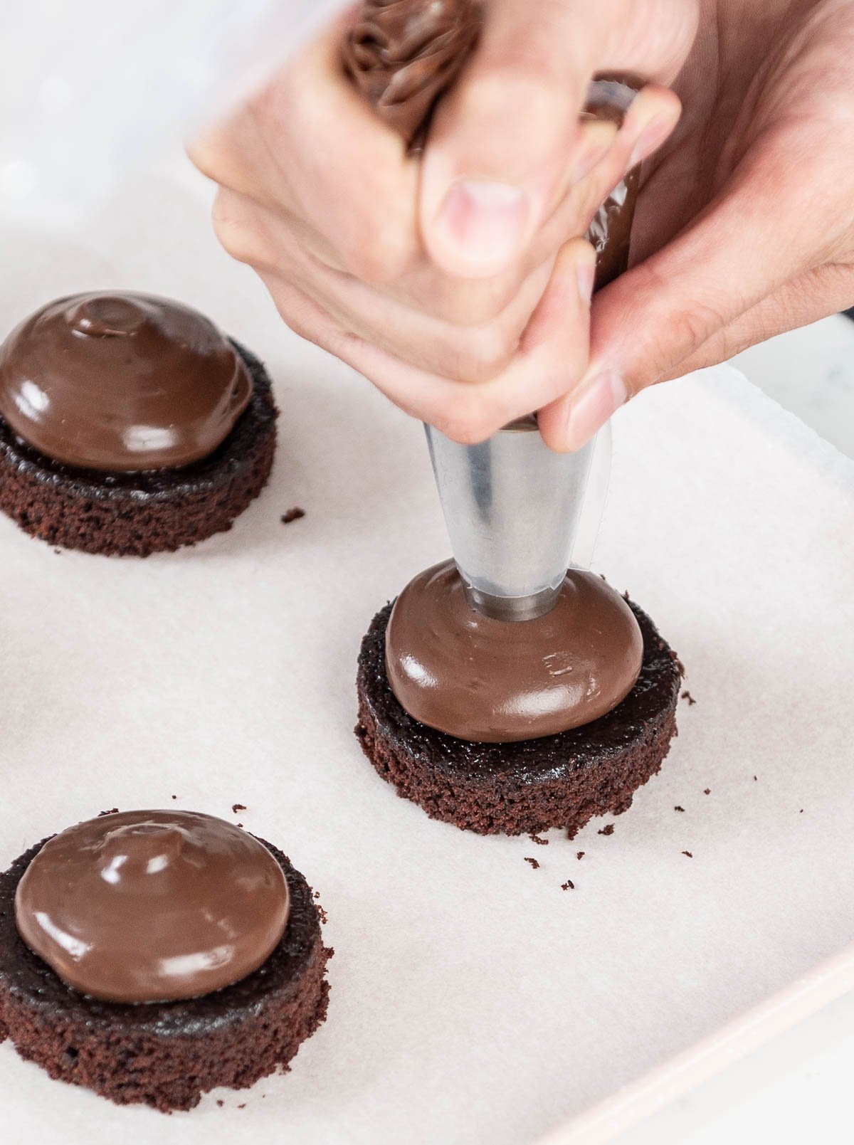 piping ganache on top of chocolate cake