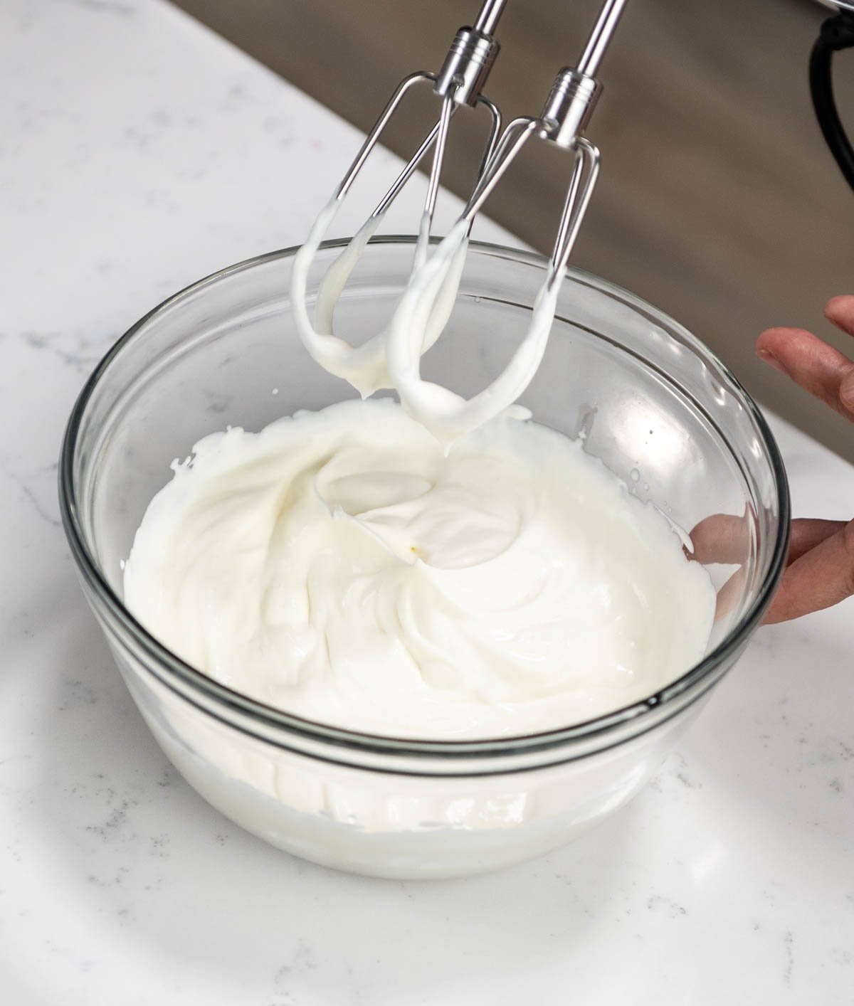 hand mixer held above bowl of whipped cream