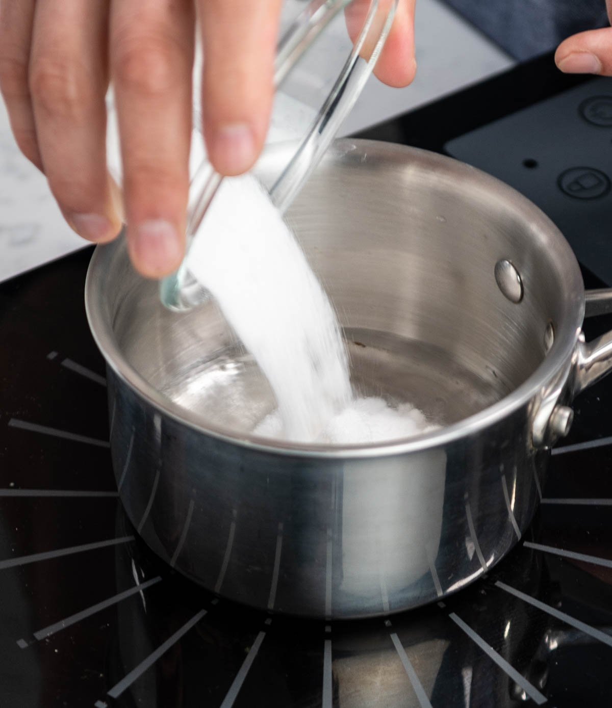 pouring sugar into saucepan
