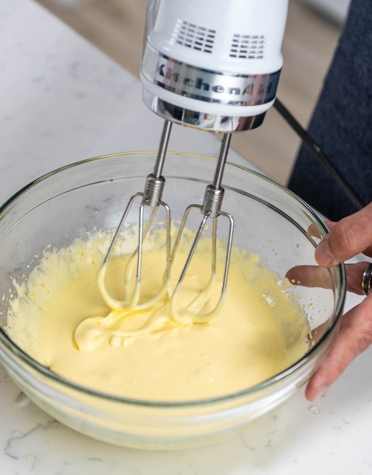 hand mixer lifted just above mixing bowl showing ribbons of batter in the bowl