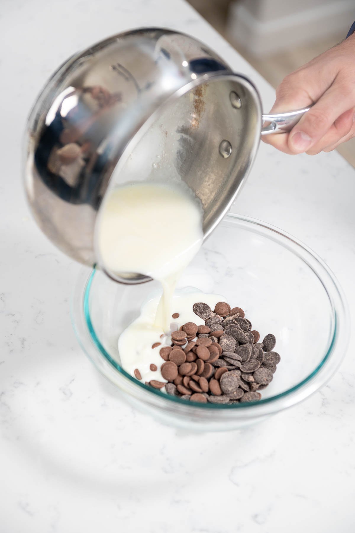 pouring cream over chocolate inside mixing bowl