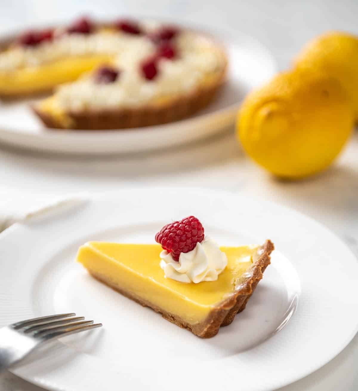 slice of lemon tart with creme fraiche and fresh raspberries