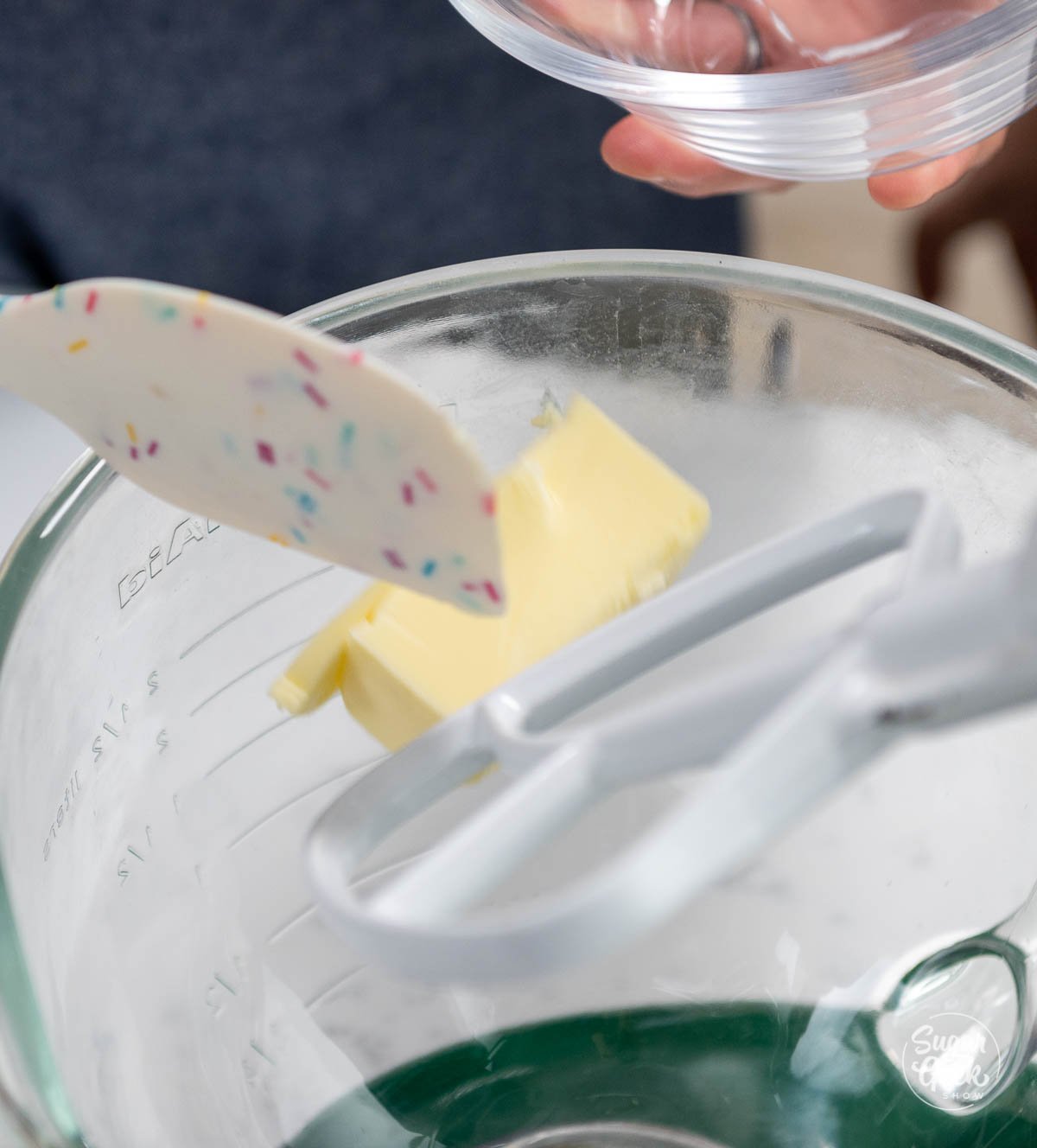 spatula placing butter into mixing bowl