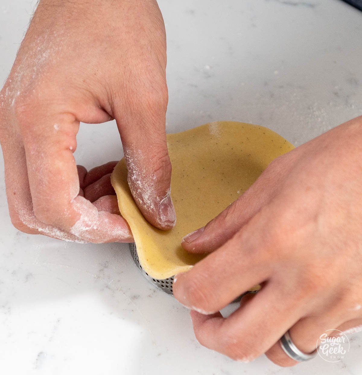fingers moving the dough into place in the tart shell