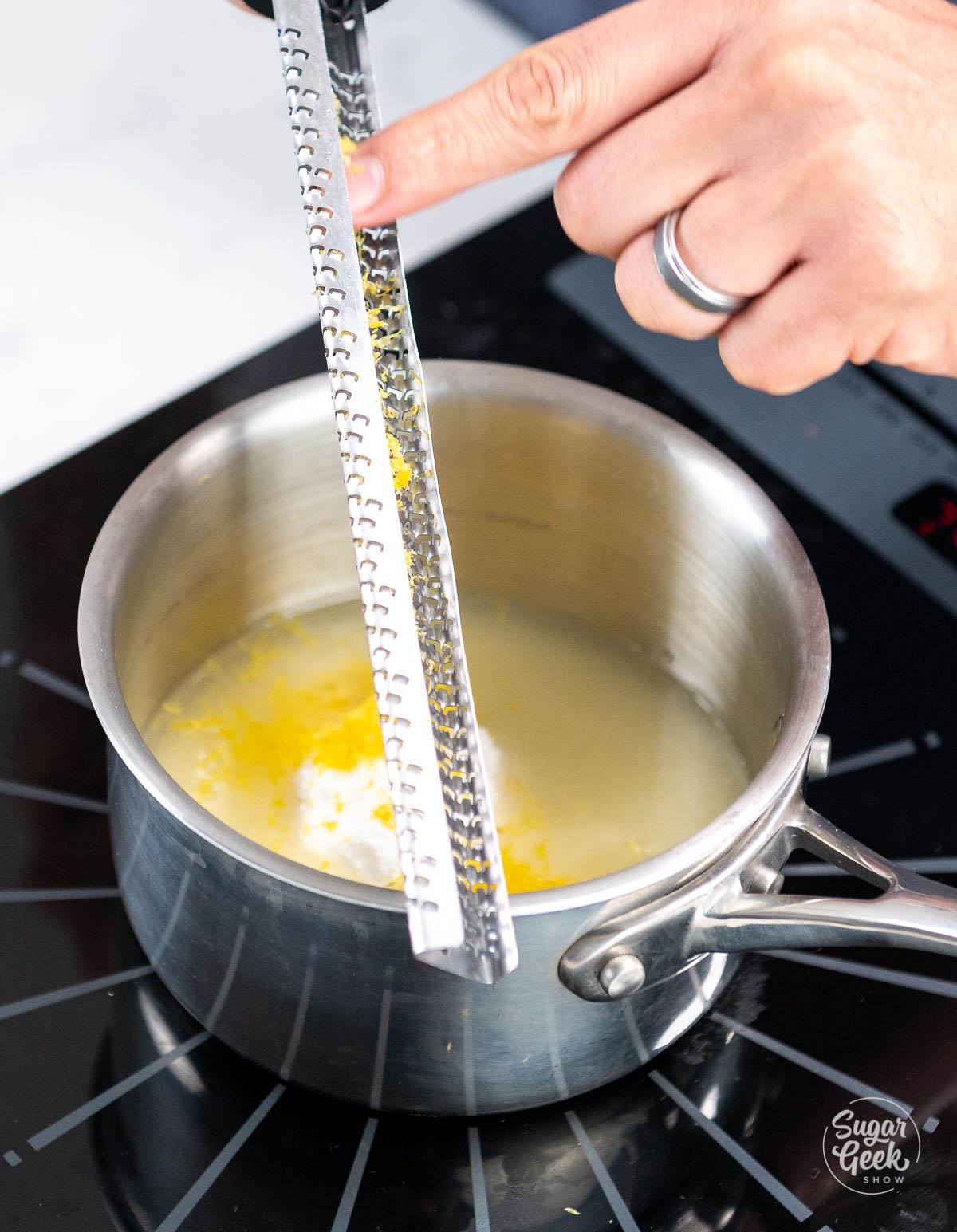 hand scraping lemon zest into sauce pan
